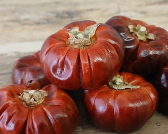 May include: A pile of six dark red, round, dried gourds with a slightly wrinkled texture.