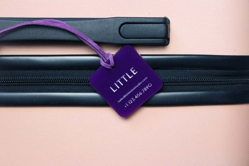 May include: Purple luggage tag with the word "LITTLE" and contact information: "hello@littledotstudio.com +1 123 456 7890"