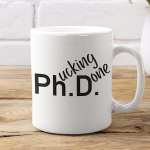 May include: White ceramic coffee mug with black text that reads "Ph.D.  Fucking Done".