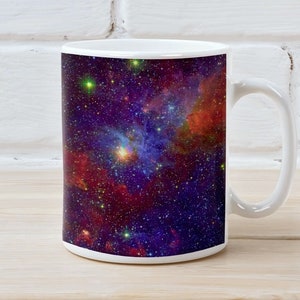 May include: White ceramic mug with a colorful nebula design. The mug features a dark blue background with red, orange, and yellow nebulae and stars.