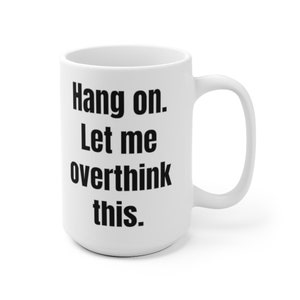 K&ouml;nnte beinhalten: Eine wei&szlig;e Keramik-Kaffeetasse mit schwarzem Text, der "Hang on. Let me overthink this." lautet.