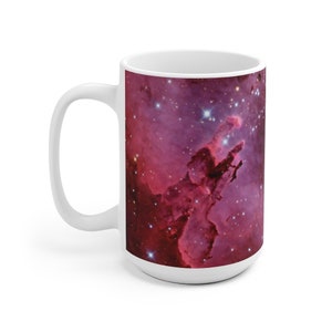 May include: White ceramic mug with a colorful image of a nebula with stars. The nebula is a vibrant pink and purple with white stars.