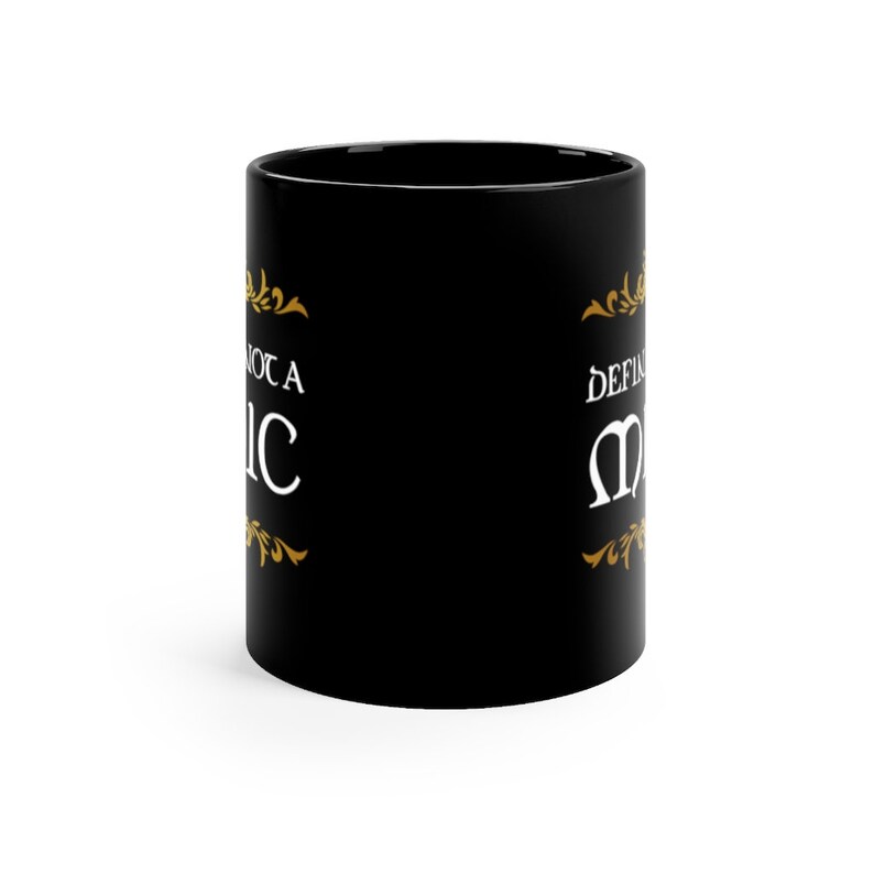 May include: Black ceramic coffee mug with a gold design and the text "Not a Basic" on the left side and "Definitely Magic" on the right side.