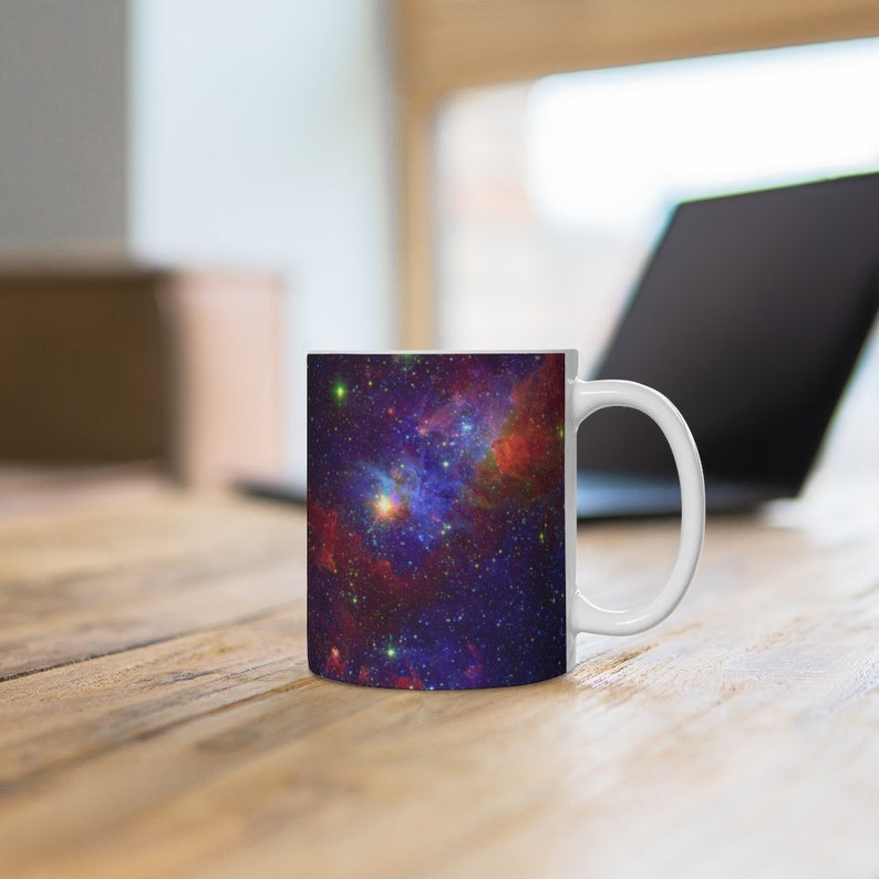 May include: White ceramic mug with a colorful nebula design. The nebula is a mix of red, blue, purple, and yellow colors with a starry background.