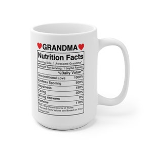 Op de afbeelding: Een witte keramische mok met een rood hart en het woord "GRANDMA" erop gedrukt. De mok heeft een voedingswaarde-etiket met een humoristische lijst van oma-kwaliteiten, zoals "Onvoorwaardelijke liefde" en "Eindeloos verwennen".