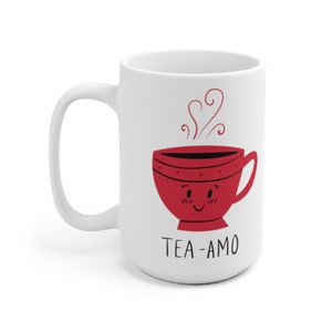 May include: White ceramic mug with a red cartoon teacup with a smiling face and steam coming out of it. The text "TEA-AMO" is printed below the teacup.