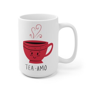 May include: White ceramic mug with a red cartoon teacup with a smiling face and steam coming out of it. The text "TEA-AMO" is printed below the teacup.