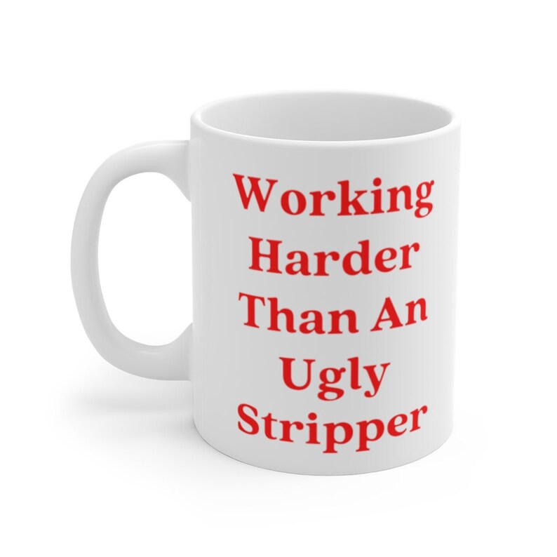 May include: White ceramic coffee mug with the text "Working Harder Than An Ugly Stripper" printed in red.