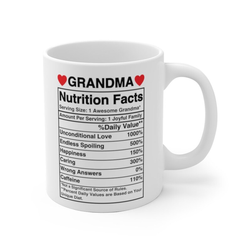 Op de afbeelding: Witte keramische mok met een rood hart en de tekst "GRANDMA" gedrukt op de voorkant. De mok heeft een voedingsschema met humoristische categorie&euml;n zoals "Onvoorwaardelijke liefde" en "Eindeloos verwennen".