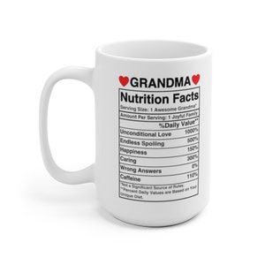 Op de afbeelding: Een witte keramische mok met een rood hart en het woord "GRANDMA" erop gedrukt. De mok heeft een voedingsschema met een humoristische lijst van oma-gerelateerde eigenschappen, zoals "Onvoorwaardelijke liefde", "Eindeloos verwennen" en "Geluk".