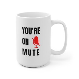 Puede incluir: Taza de cer&aacute;mica blanca con texto negro que dice "You're on mute" y un icono de micr&oacute;fono rojo con una l&iacute;nea diagonal.