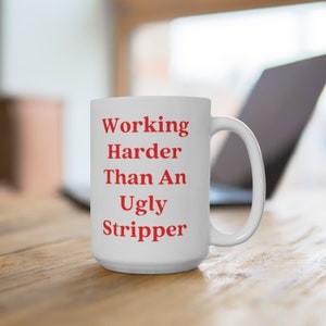May include: White ceramic coffee mug with the text "Working Harder Than An Ugly Stripper" in red lettering.