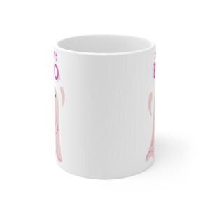 May include: White ceramic mug with a pink ghost illustration and the text "Spooky Boo" in pink lettering.