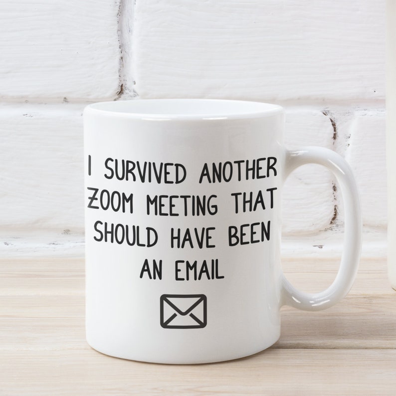 May include: White ceramic coffee mug with black text that reads "I survived another zoom meeting that should have been an email" with an envelope icon below the text.