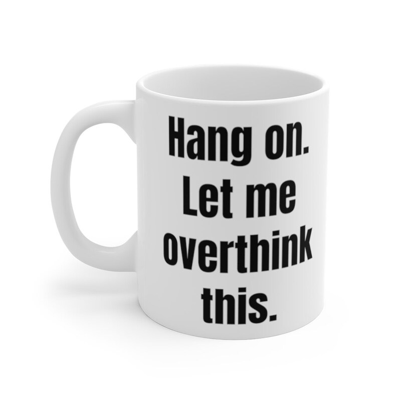 K&ouml;nnte beinhalten: Eine wei&szlig;e Keramik-Kaffeetasse mit schwarzem Text, der "Hang on. Let me overthink this." lautet.