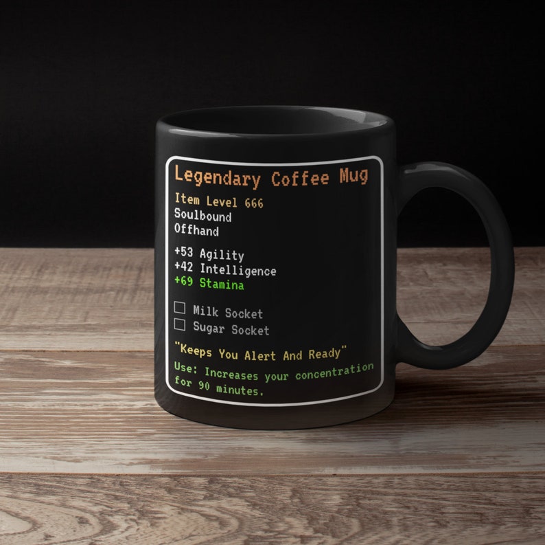 May include: Black coffee mug with a video game-style design. It reads "Legendary Coffee Mug", "Item Level 666", "Soulbound", "Offhand", "+53 Agility", "+42 Intelligence", "+69 Stamina", "Milk Socket", "Sugar Socket", "Keeps You Alert And Ready", "Use: Increases your concentration for 90 minutes."