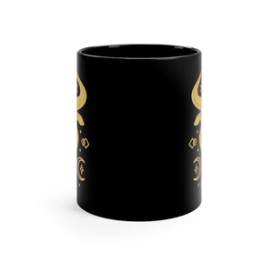 May include: Black ceramic mug with a gold design of a crescent moon, stars, and geometric shapes.