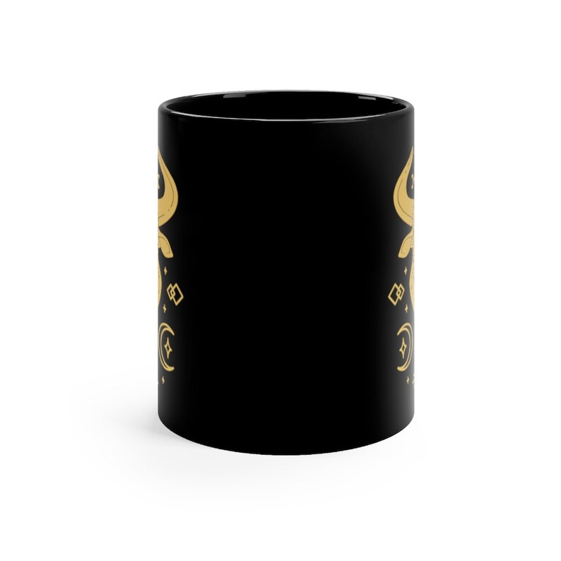 May include: Black ceramic mug with a gold design of a crescent moon, stars, and geometric shapes.