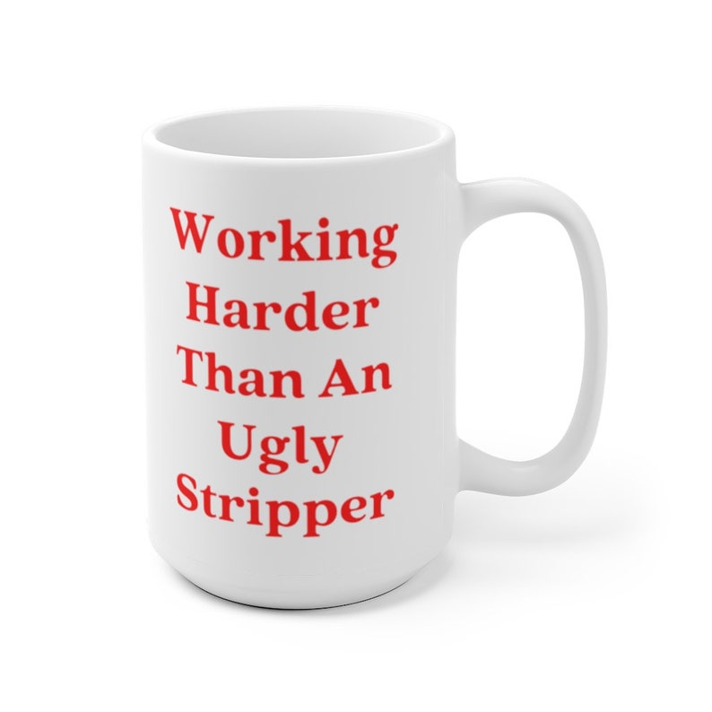 May include: White ceramic coffee mug with a red inscription that reads "Working Harder Than An Ugly Stripper".