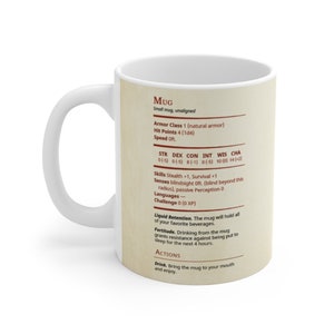May include: White ceramic mug with a brown and red design. The mug has a Dungeons and Dragons character sheet with the title "Mug" and stats like "Armor Class", "Hit Points", "Speed", "STR", "DEX", "CON", "INT", "WIS", "CHA", "Skills", "Senses", "Languages", "Challenge", "Liquid Retention", "Fortitude", and "Actions".