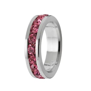 May include: A silver ring with a band of pink crystals around the center.