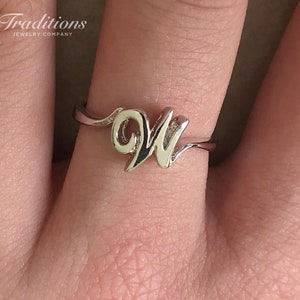 Puede incluir: Un anillo de plata con un diseño de letra cursiva "W".