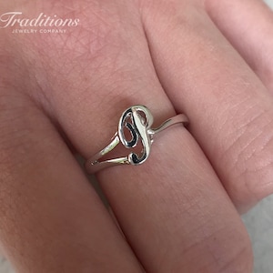 May include: A silver ring with a cursive letter "P" design.