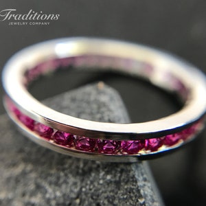 May include: A silver band ring with a row of pink gemstones set in the band.