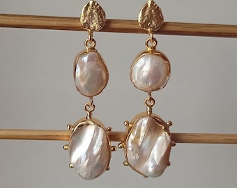 May include: A pair of gold earrings with two white baroque pearls on each earring. The pearls are attached to a gold chain and the earrings have a gold leaf design at the top.
