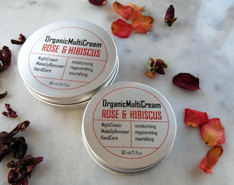 May include: Two silver tins of Organic MultiCream Rose & Hibiscus face cream. The smaller tin is 60 ml/2 fl oz and the larger tin is 100 ml/3.4 fl oz. The cream is described as a night cream, makeup remover, and hand care product. It is also described as moisturizing, regenerating, and nourishing.