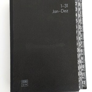 May include: A black organiser with labelled tabs for each day of the month, from 1-31. The cover has the text "1-31 Jan-Dez" and the ELBA logo. The tabs are labelled with the months and days.