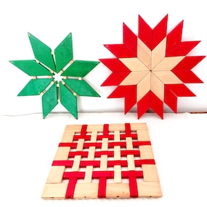 Peut inclure: Trois objets décoratifs en bois : deux ornements en forme d'étoile et un tapis tissé. Une étoile est verte, l'autre est rouge et en bois naturel. Le tapis est tissé avec des lanières rouges et en bois naturel. Tous les articles sont sur fond blanc.
