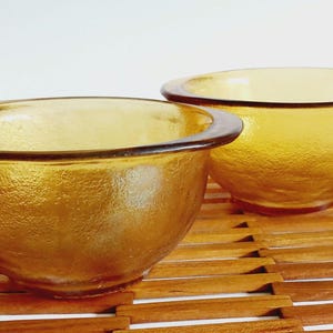 Op de afbeelding: Een set van drie keramische mokken met een gespikkelde, matte afwerking. De mokken zijn in tinten crème, lichtgrijs en donkergrijs. Elke mok heeft een eenvoudig, minimalistisch ontwerp en een afgeronde handgreep. De mokken zijn op elkaar gestapeld.