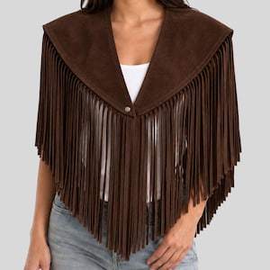 Puede incluir: Un poncho de ante marrón oscuro con un escote en V profundo, un cierre de botón a presión de metal plateado en el centro y detalles de flecos largos y finos que se extienden desde los hombros hasta un dobladillo en punta al frente.