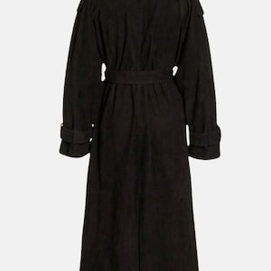 May include: A long black trench coat featuring a wide collar, long sleeves with buckled cuffs, and a matching tie belt at the waist. The coat has a structured shoulder design and a full-length silhouette, captured from the back view.