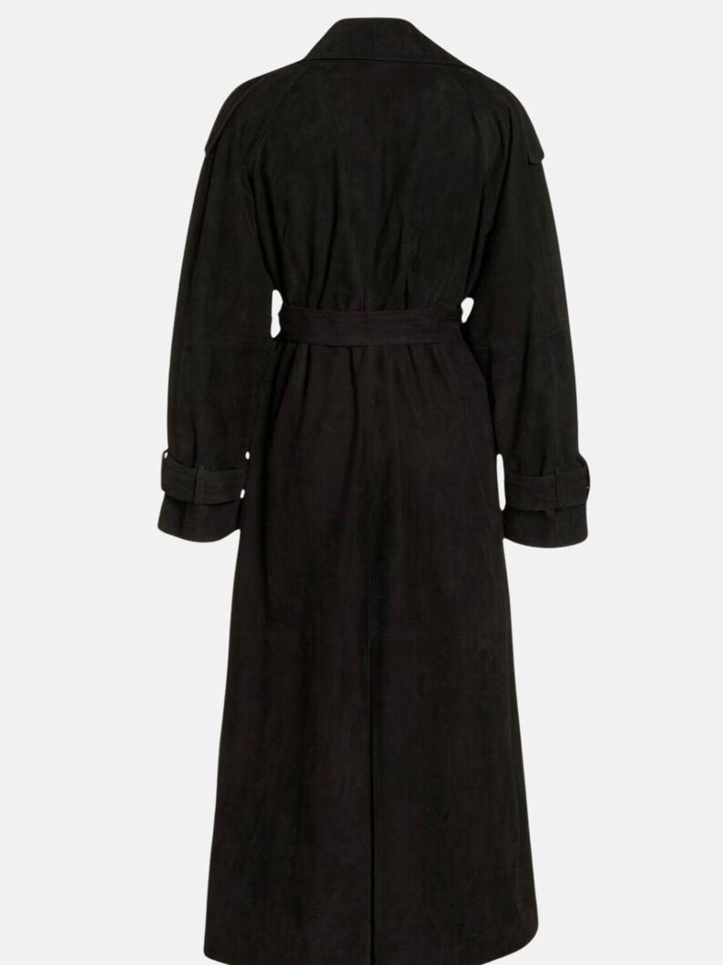 May include: A long black trench coat featuring a wide collar, long sleeves with buckled cuffs, and a matching tie belt at the waist. The coat has a structured shoulder design and a full-length silhouette, captured from the back view.
