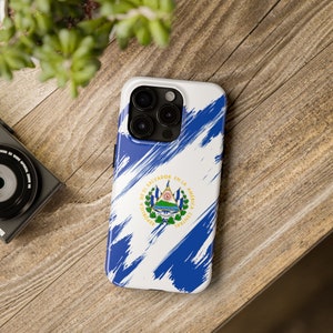 May include: A white phone case with a blue and white abstract design featuring the El Salvador flag. The flag has the words "Republica de El Salvador en la America Central" around the coat of arms.