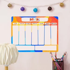 Può includere: Un colorato planner settimanale con il nome "Davide" in alto. Il planner ha uno sfondo bianco con sezioni per ogni giorno della settimana, delineate in blu. Il bordo è un mix di arancione, giallo e blu.