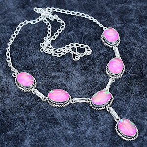 Puede incluir: Un collar plateado con piedras preciosas rosas de forma ovalada. Las piedras están engastadas en un bisel decorativo y unidas por una delicada cadena. Cierre de mosquetón.
