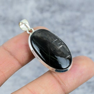 May include: A silver pendant with a black oval gemstone. The gemstone has a striated pattern.