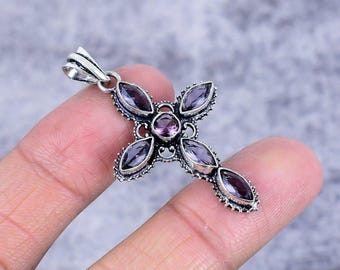 May include: A silver cross pendant with a purple amethyst gemstone in the center and smaller amethyst gemstones around the edges.