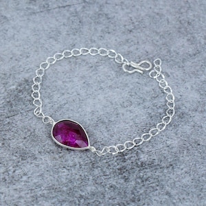 Peut inclure: Un bracelet en chaîne argent avec une seule pierre précieuse violette en forme de larme.
