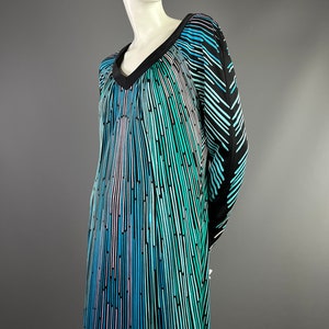 Peut inclure: Une robe &agrave; manches longues avec un col en V et un motif g&eacute;om&eacute;trique de rayures verticales dans des tons de bleu, vert et noir.