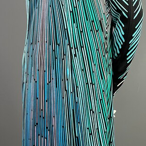 Peut inclure: Une robe noire avec un motif abstrait bleu, vert et blanc. Le motif est compos&eacute; de fines lignes qui cr&eacute;ent un effet ray&eacute;.