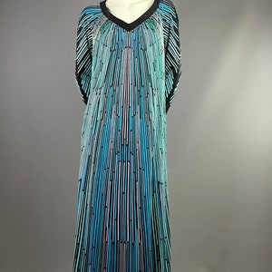 Peut inclure: Une longue robe fluide avec un col en V et un motif ray&eacute; noir, bleu et blanc. La robe a une coupe ample et fluide et est faite d'un tissu l&eacute;ger.