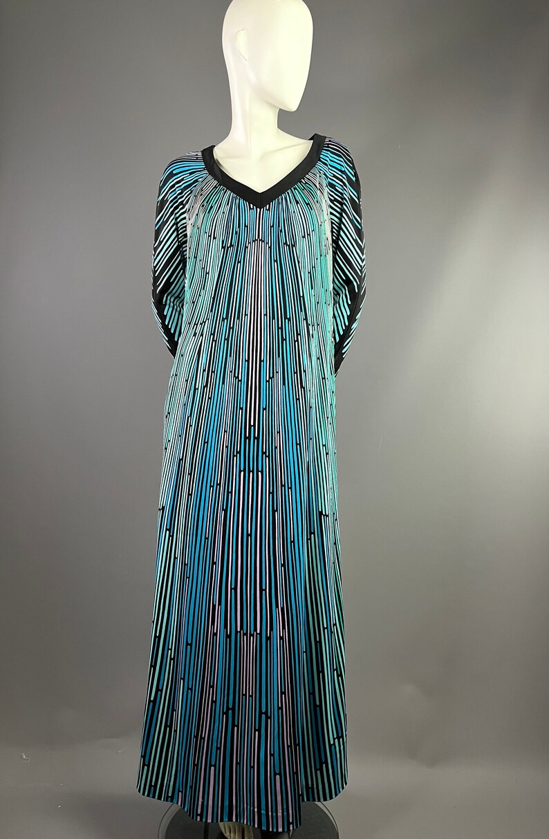 Peut inclure: Une longue robe fluide avec un col en V et un motif ray&eacute; noir, bleu et blanc. La robe a une coupe ample et fluide et est faite d'un tissu l&eacute;ger.