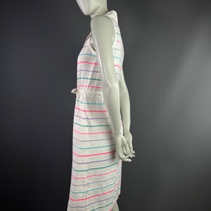 May include: A white sleeveless dress with horizontal stripes in pink, green, and purple. The dress has a drawstring waist and a collared neckline.