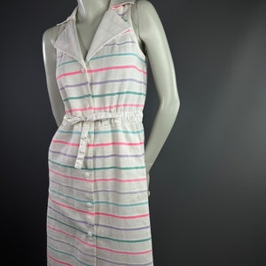 May include: A white sleeveless dress with a collared neckline and a button-up front. The dress has a striped pattern in pink, green, and purple.