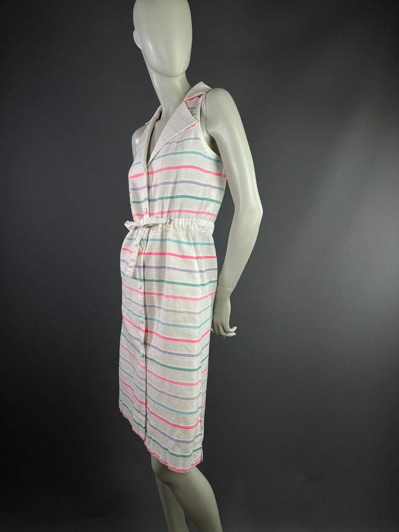 May include: A white sleeveless dress with a button-up front and a tie belt. The dress has horizontal stripes in pink, green, and purple.