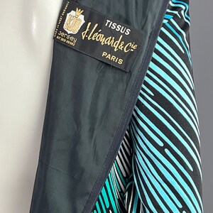 Peut inclure: Une veste ray&eacute;e noire et bleue avec une &eacute;tiquette indiquant "Tissus J. Leonard & Cie Paris" et "Jersey mit der Krone Made in West Germany".